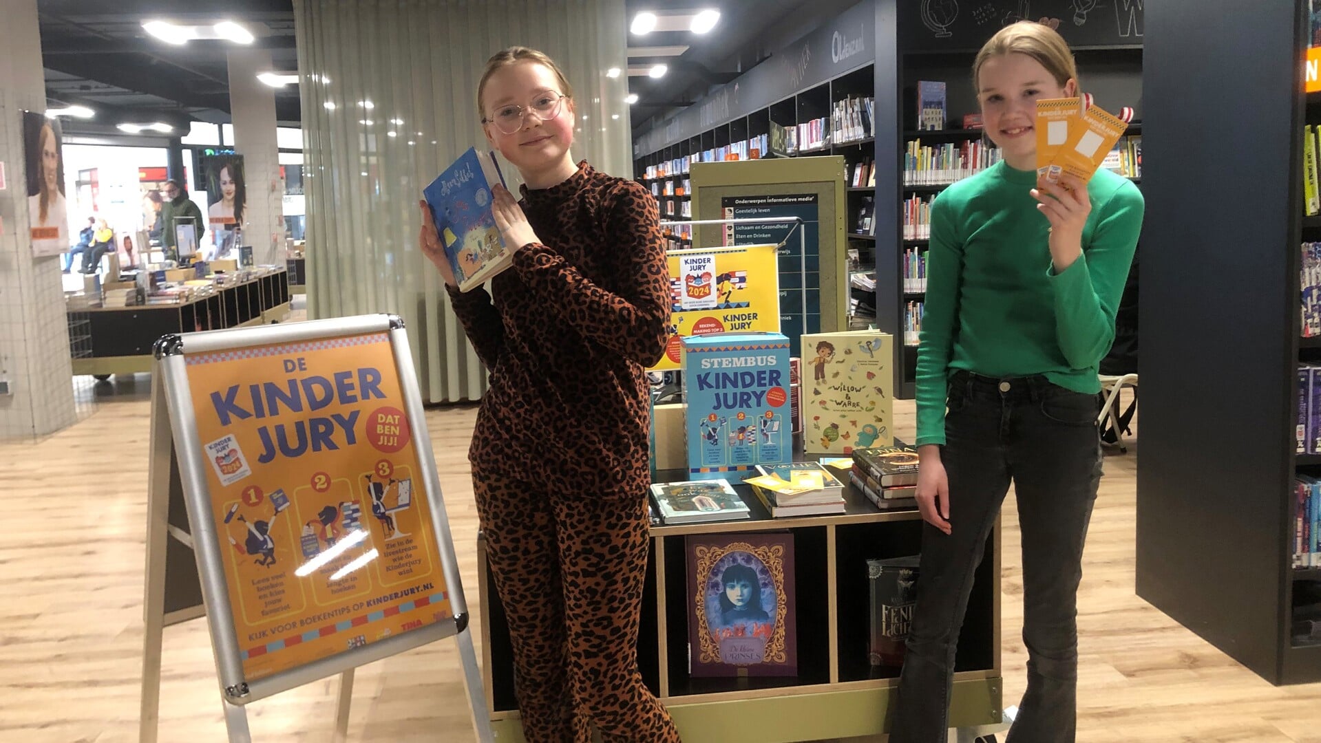 Fanatieke lezers Saar Grundel (rechts) en Suus Bakker van basisschool de Leemstee in Bibliotheek Oldenzaal bij de display tafel Kinderjury 2024.