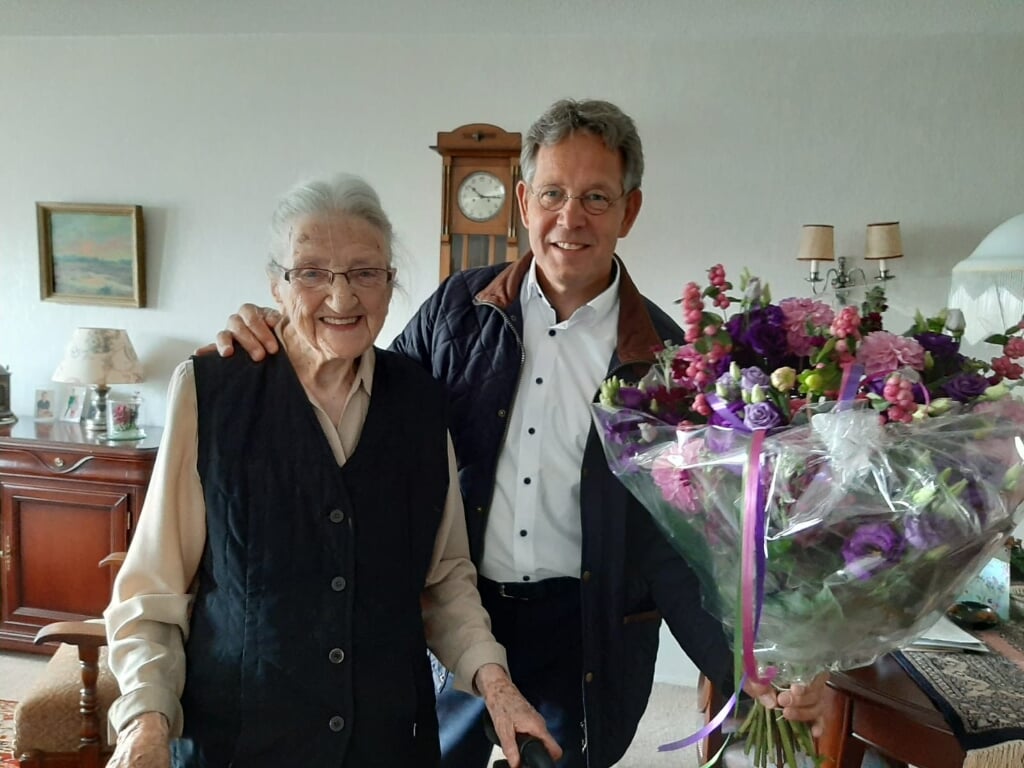 Juffrouw Fraassen wordt namens de gemeente gefeliciteerd door gemeentebode Erik Brinks. De opname is in 2020 gemaakt toen ze 103 jaar werd. 