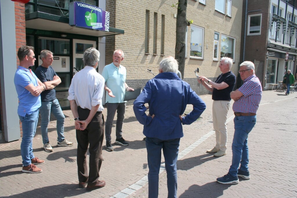 Willy Brons geeft uitleg in de Steenstraat over het oorlogsverleden. Een aandachtige groep toehoorders neemt de boeiende geschiedenis tot zich tijdens de wandeling.