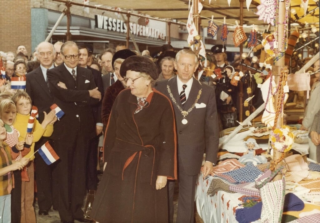Koningin Juliana in Rijssen op 10 september 1975. Naast haar burgemeester G. J. Smit. Het gezelschap loopt door de Rozengaarde. Op de achtergrond supermarkt Wessels ('n Snuwer) (Foto: Erfgoed Rijssen-Holten).