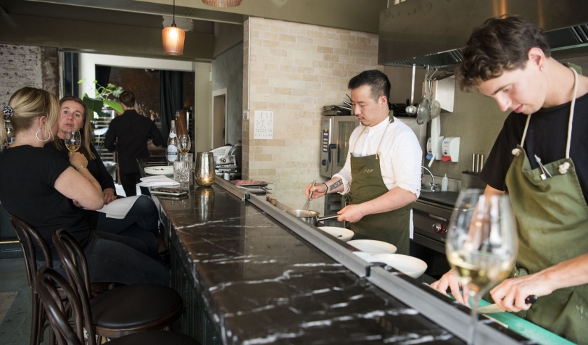 Eigenaar Jin Hu (links) en Bob van Bree van restaurant The Green Rose bereiden gerechten voor. Kyonne (links) en Chrissie praten elkaar bij. (foto: Ellen Koelewijn)
  