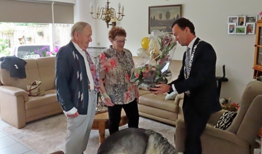 <p>Burgemeester Lucien van Riswijk feliciteert Wim en Lies Derksen met een grote bos bloemen. (foto: PR)</p>  