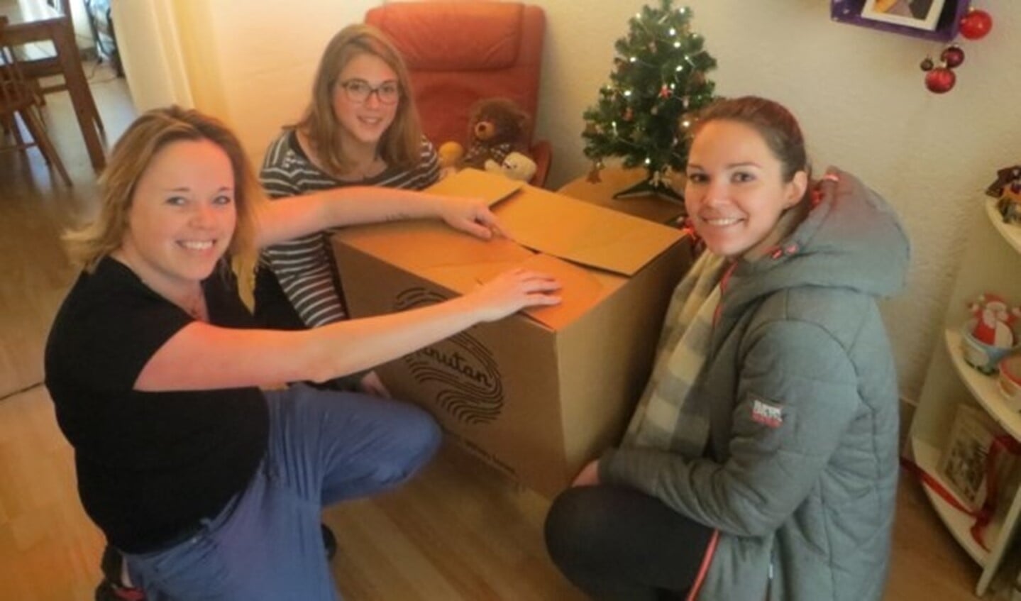 Djen (links) is dolblij met haar kerstpakket. De meiden van het Wijkteam Carnisse kwamen hem speciaal brengen met achter Coco Bastiaansen en voor stagiair Nathalie Meijers (22). (foto: Willeke Havenaar)