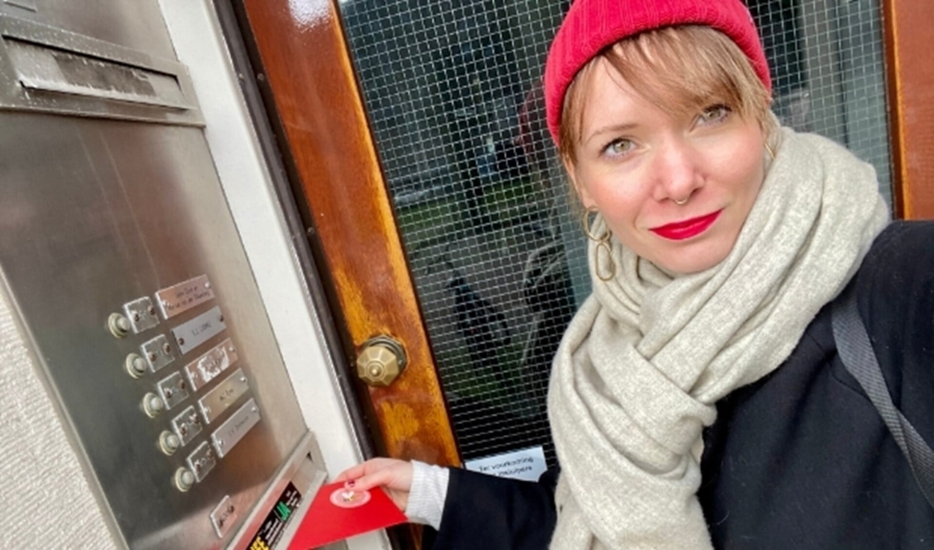 Kelly Leeuwis, bedenker van de Valentijn Buurtpost, doet een kaartje in de bus van een buurtgenoot.