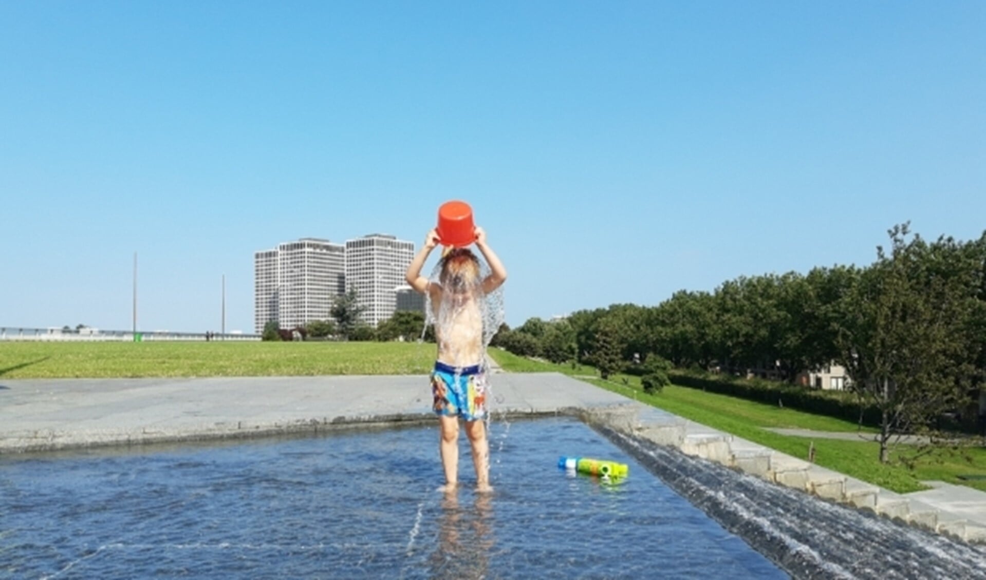 Jongetje giet emmer water over zich heen op het Dakpark