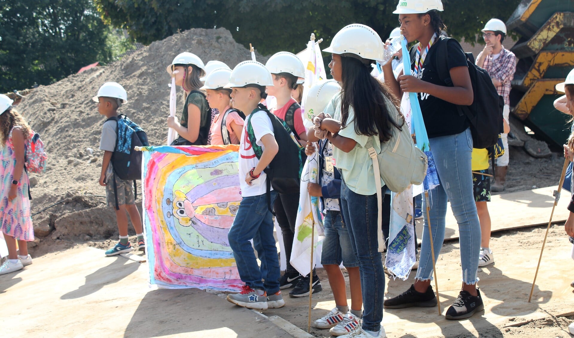 Een groep kinderen stond klaar om met een eigen ontworpen vlag het bouwterrein op te gaan tijdens de ceremonie voorafgaand aan het slaan van de eerste paal. Foto: Annemarie van der Ploeg 
