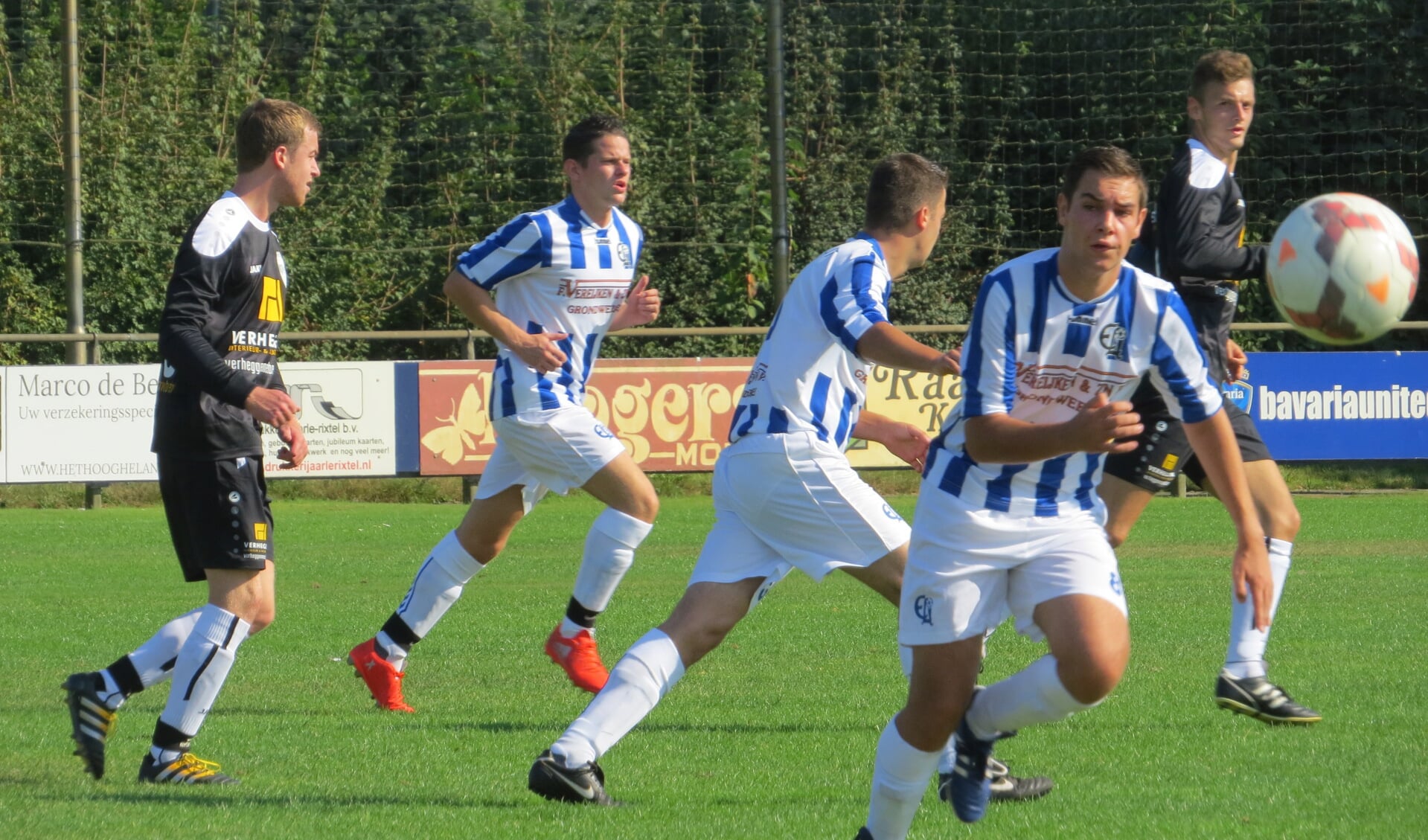 Frank van Berlo bij de bal, op de achtergrond in het blauw-wit Roel van Mook en in het midden Bas Hollanders.