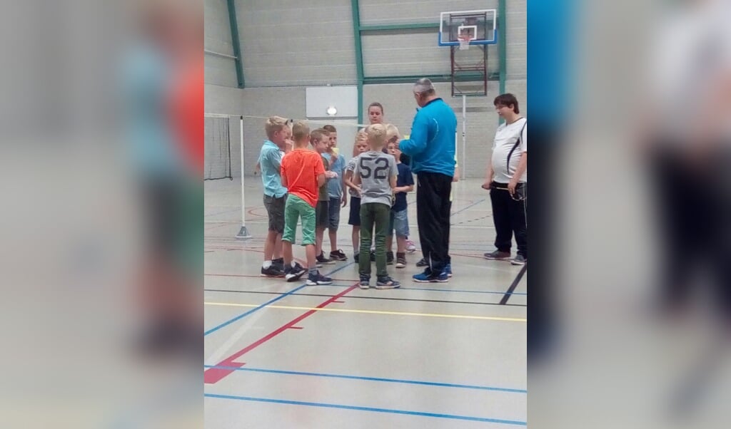 Trainer Frans van Waardenburg (midden) geeft een introductie aan de groep Roefelende kinderen. Begeleider Tim van Bommel luistert aandachtig mee