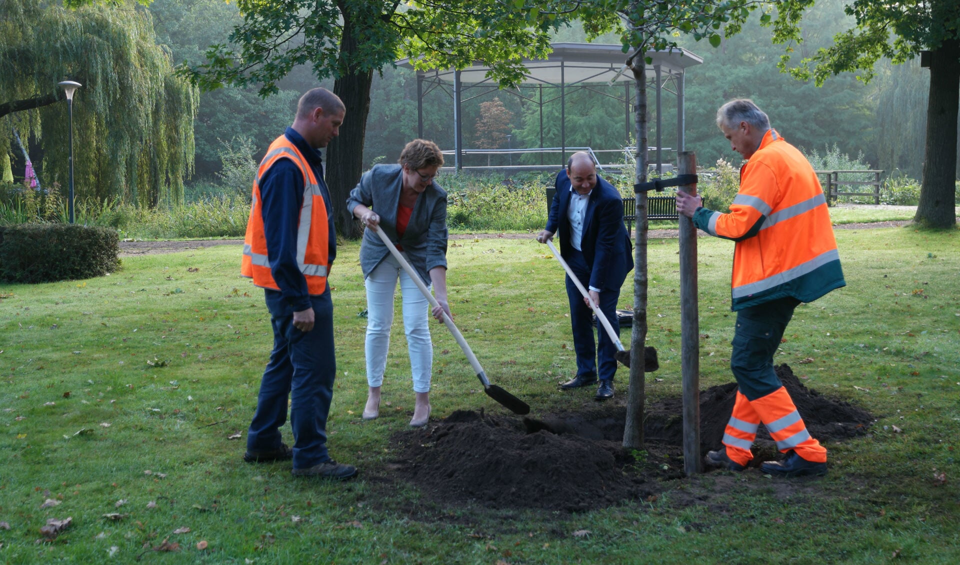 Wethouder Buter (2e van links) en Paul Verbakel (2e van rechts) planten een boom in het kader van de vernieuwde samenwerking