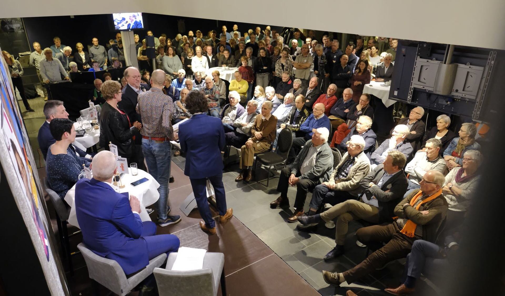 Een volle zaal in het gemeentehuis. Links op de voorgrond de lijsttrekkers van de 6 politieke partijen die meedoen in de gemeente Laarbeek