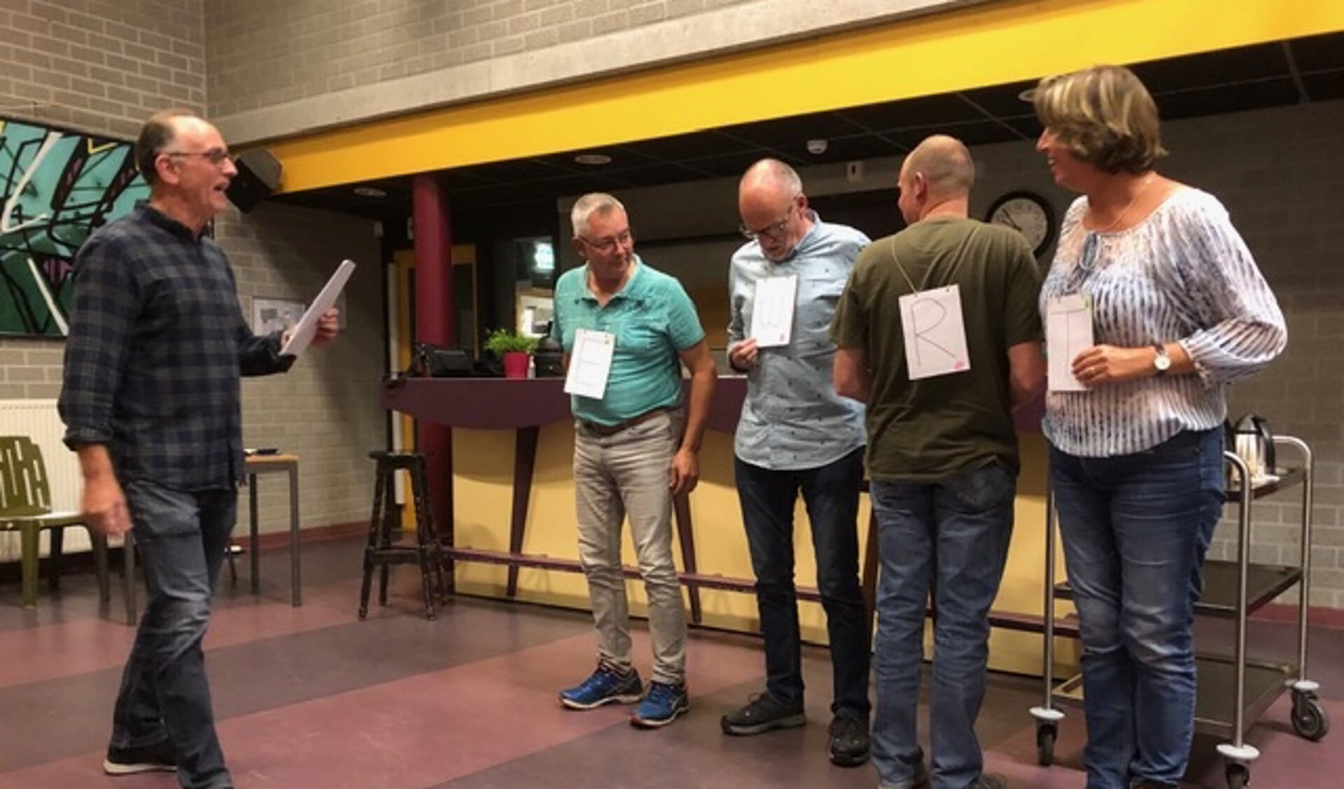 Organisator Martijn Junggeburth (l) instrueert de deelnemers tijdens het hilarische letterspel