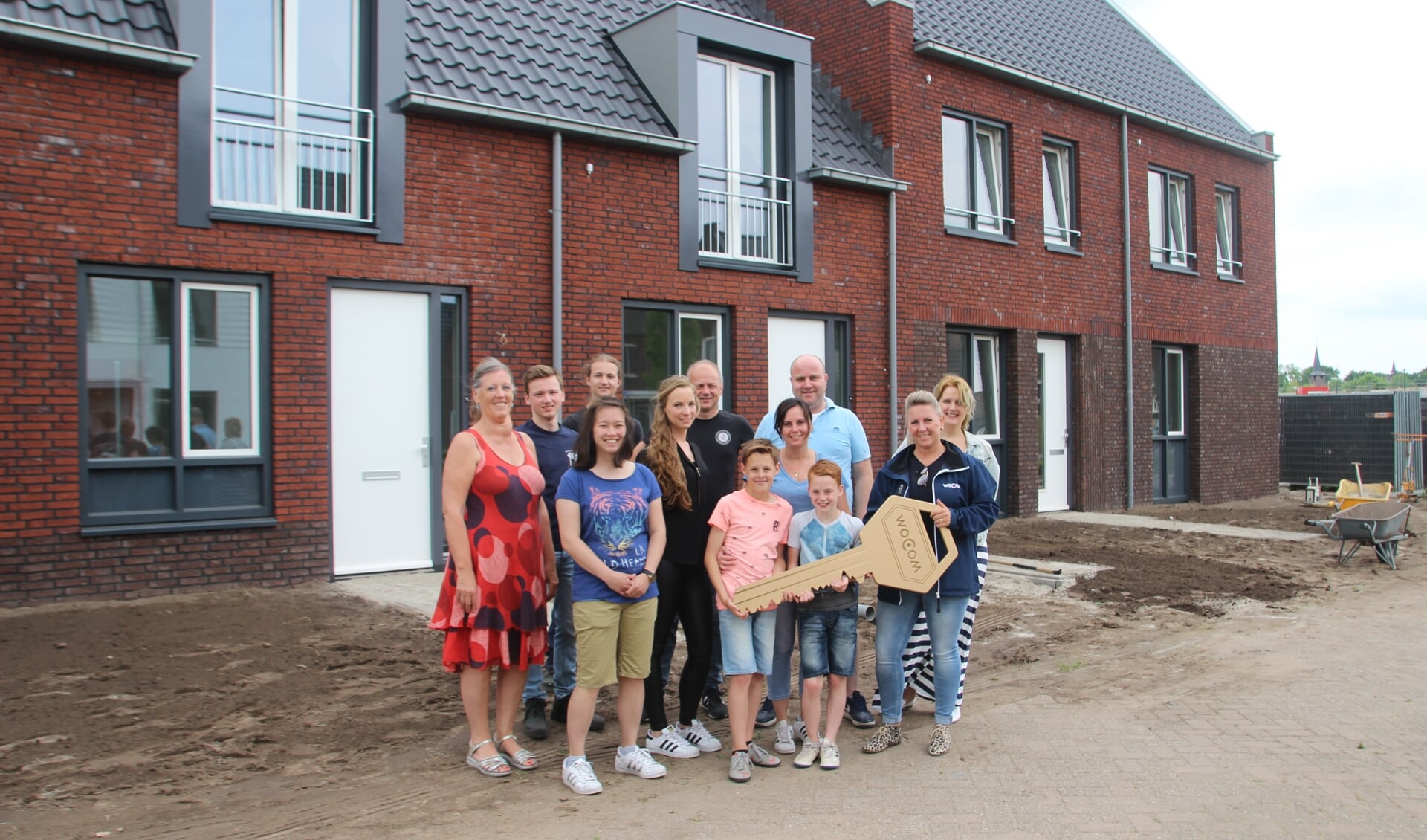 woCom-medewerkster Hanneke Consent - Van Hout overhandigt symbolisch de eerste sleutel aan enkele bewoners van de eerste energieneutrale huurwoningen van Laarbeek