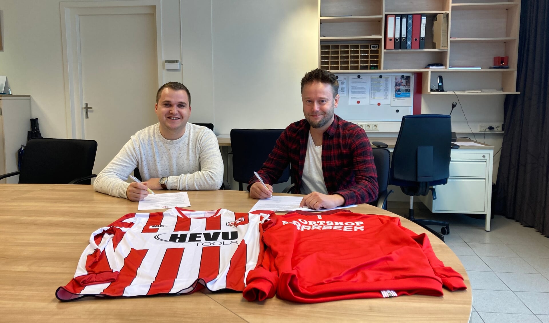 Joey van den Heuvel (Hevu) en Bas Roos (Sportshop Laarbeek) ondertekenen de contracten.