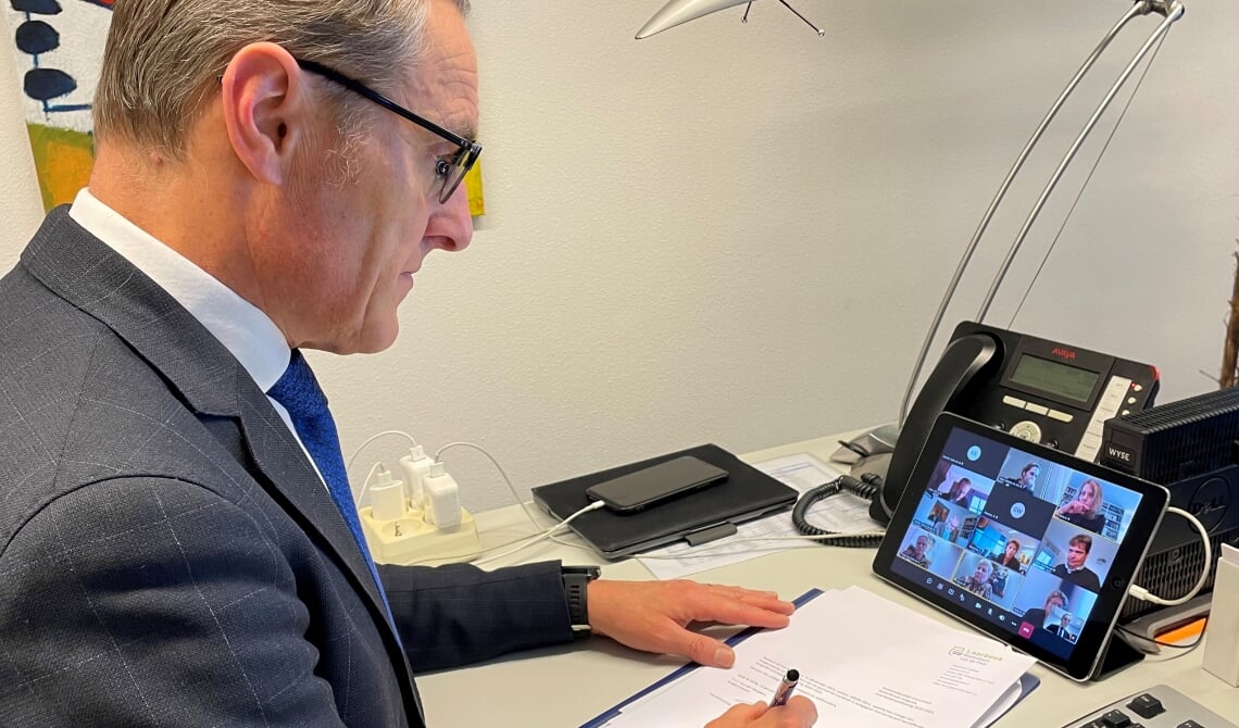 <p>Burgemeester Frank van der Meijden woont de digitale bijeenkomst met de burgemeesters in Peelland bij terwijl hij zijn handtekening zet onder het convenant.</p>