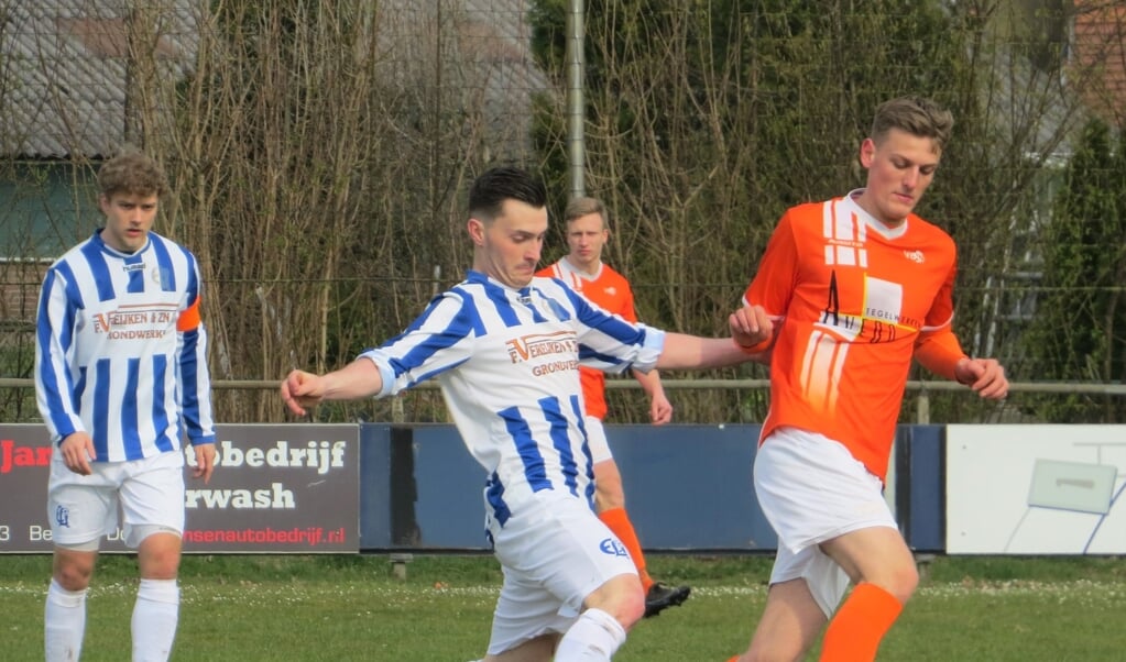 Randy v.d. Groef in duel om de bal; aanvoerder Coen Brouwers kijkt toe. 