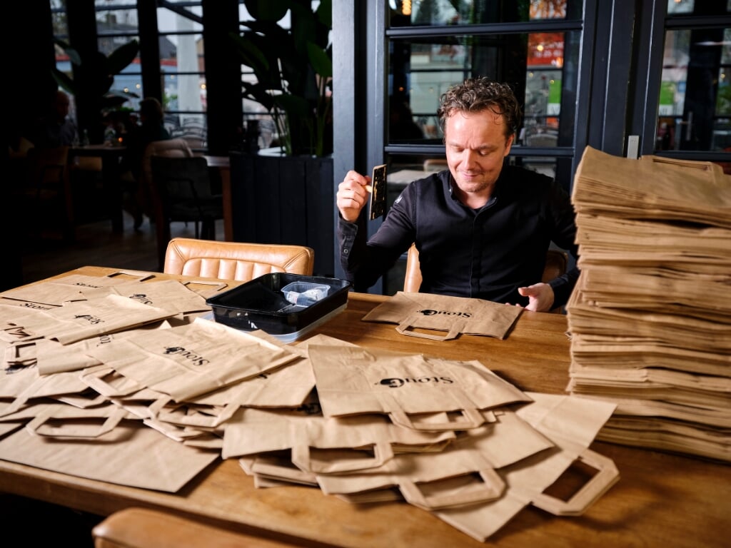 Chef Roland Lorenzini van restaurant Stout is de tassen aan het stempelen die gebruikt worden voor de afhaalmaaltijden
