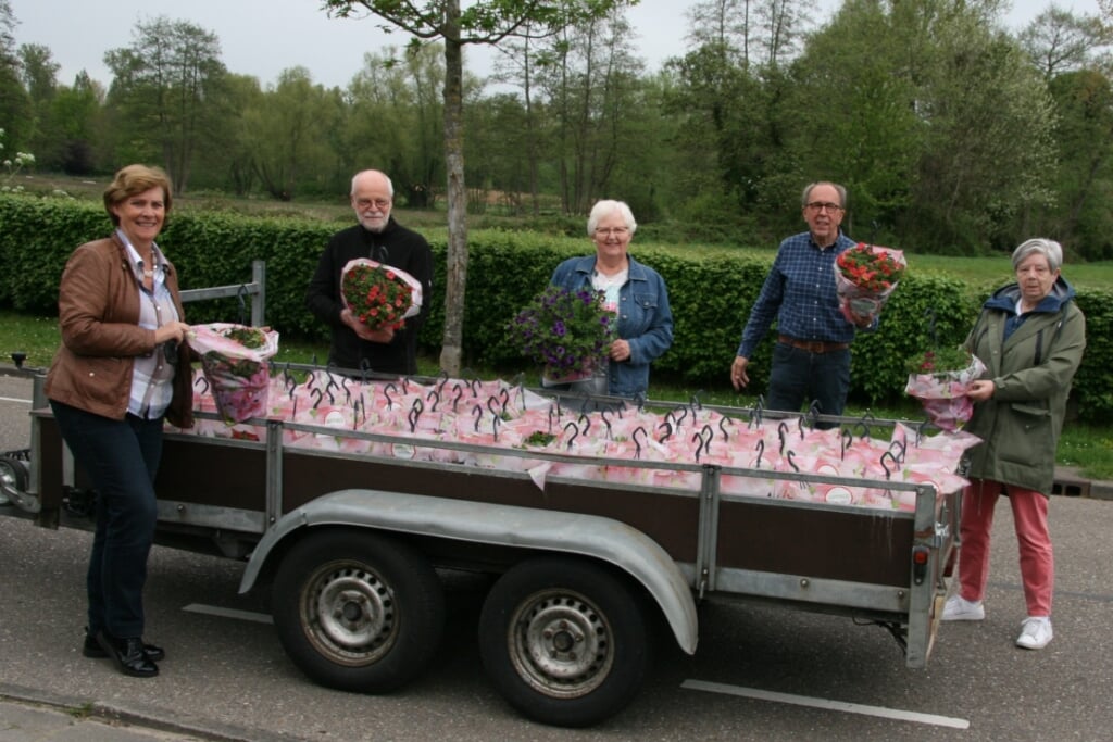 Vrijwilligers van de Zonnebloem delen bloemetjes uit.