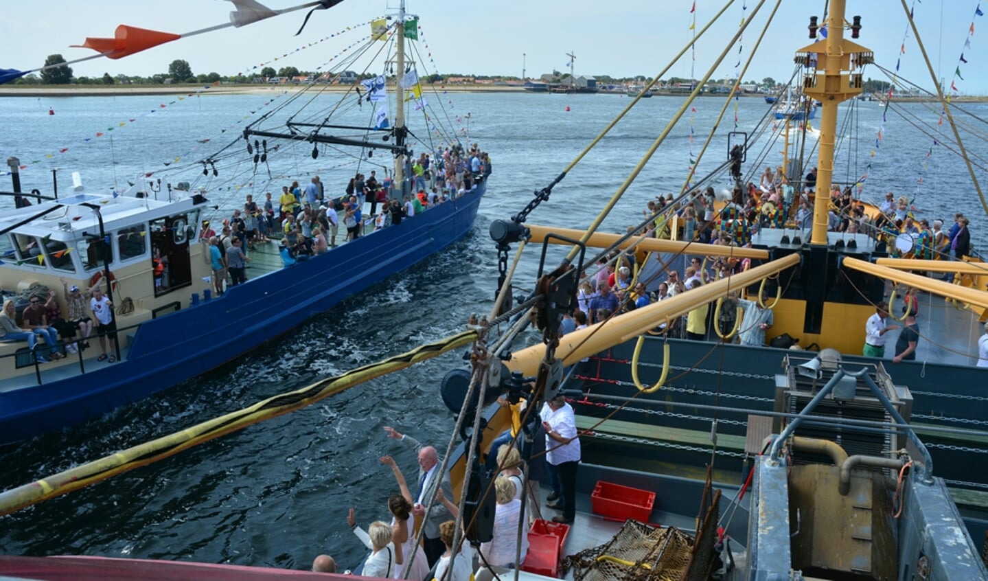 Bij terugkeer naar de haven komen de mosselkotter langs vlaggenschip BRU 33, waar mosselkoningin 2015 Erika Schot en voorzitter Theo Ketting van Stichting Festiviteiten Bruinisse staan te zwaaien.