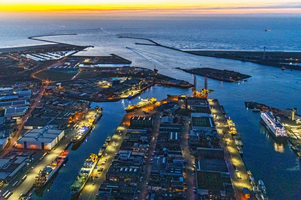 H De avond valt over het havengebied van IJmuiden. Het zevental vriestrawlers voor de kant in de Haringhaven en de aanloop daarvan valt goed op. (Foto: Flying Focus)