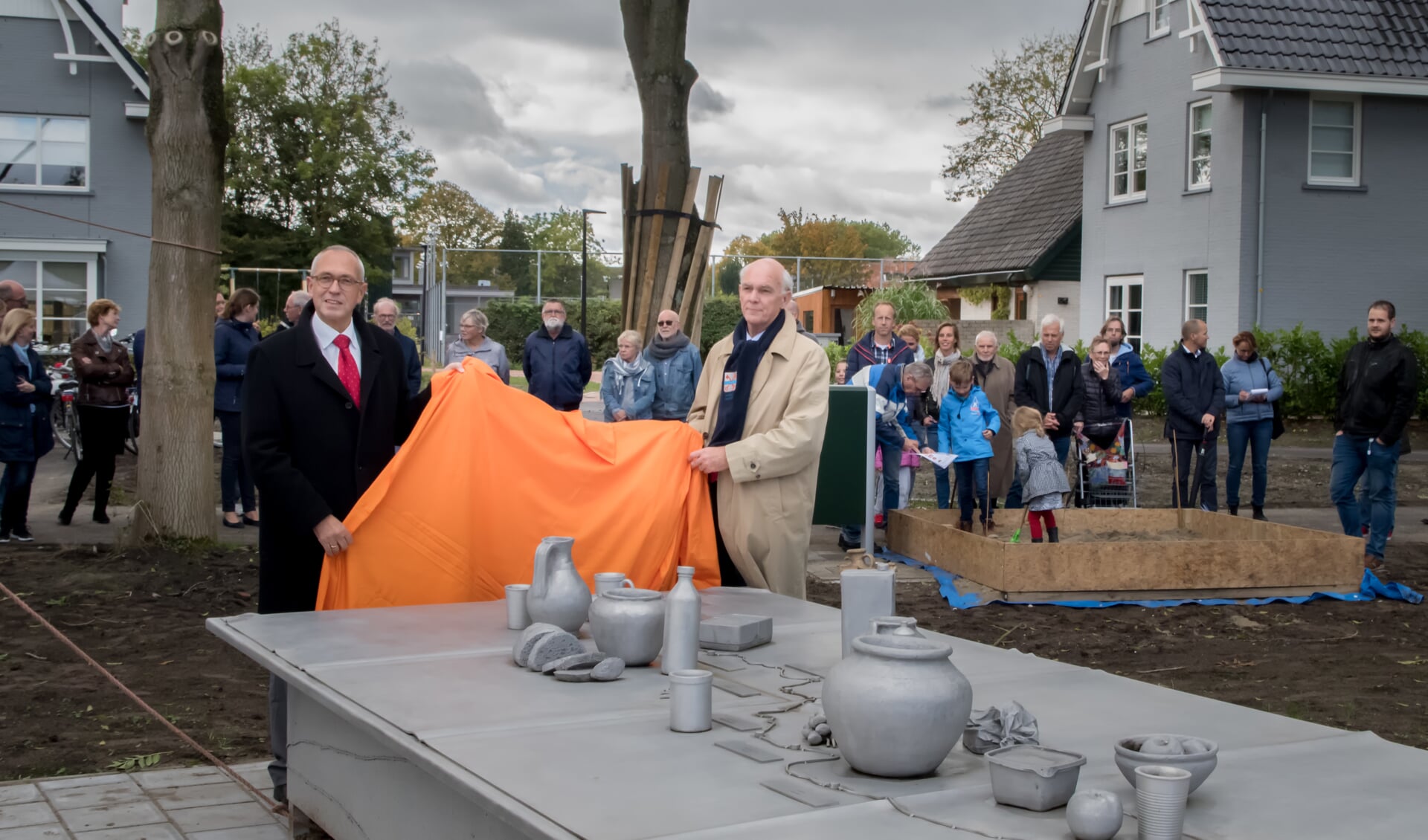 Voor een klein publiek van nieuwe bewoners en andere belangstellenden trokken wethouders Wassenaar (links) en  Gardeniers donderdag samen het oranje zeil weg dat het kunstwerk bedekte. | Foto: J.P. Kranenburg