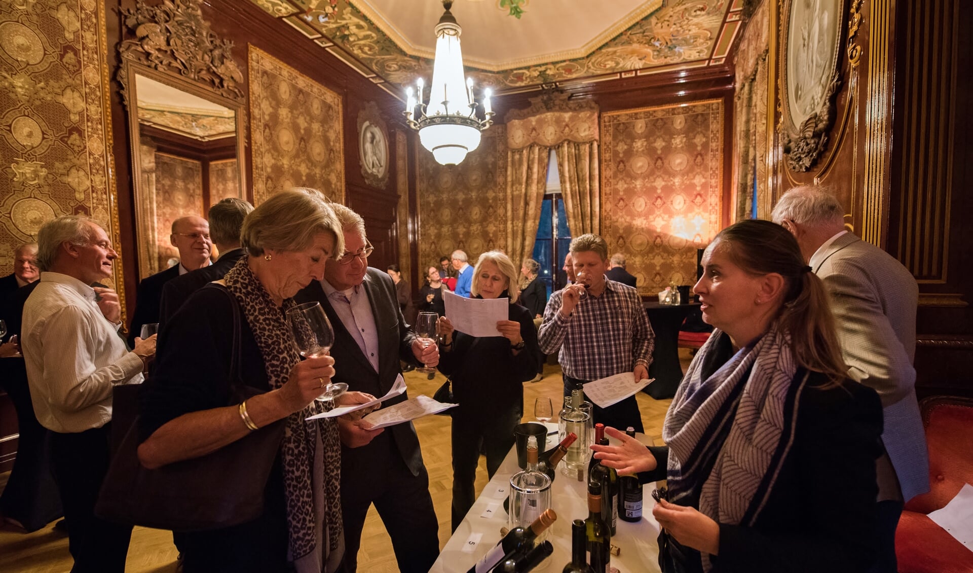 Bezoekers van de door de Lionsclub georganiseerde proeverij krijgen uitleg over de zeer diverse wijnen. | Foto: Thibault Verlinden
