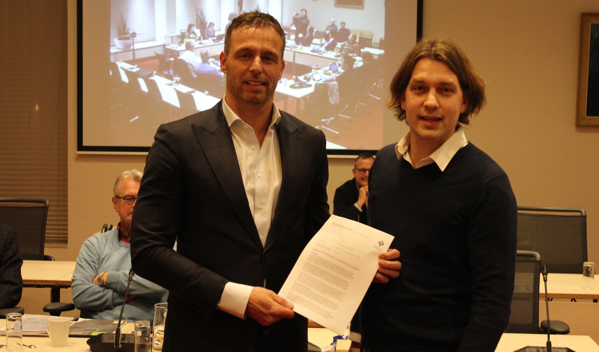Raadslid Maarten van Welie (CDA) overhandigt het initiatiefvoorstel aan wethouder Bas Brekelmans (links). | Foto: Nico Kuyt