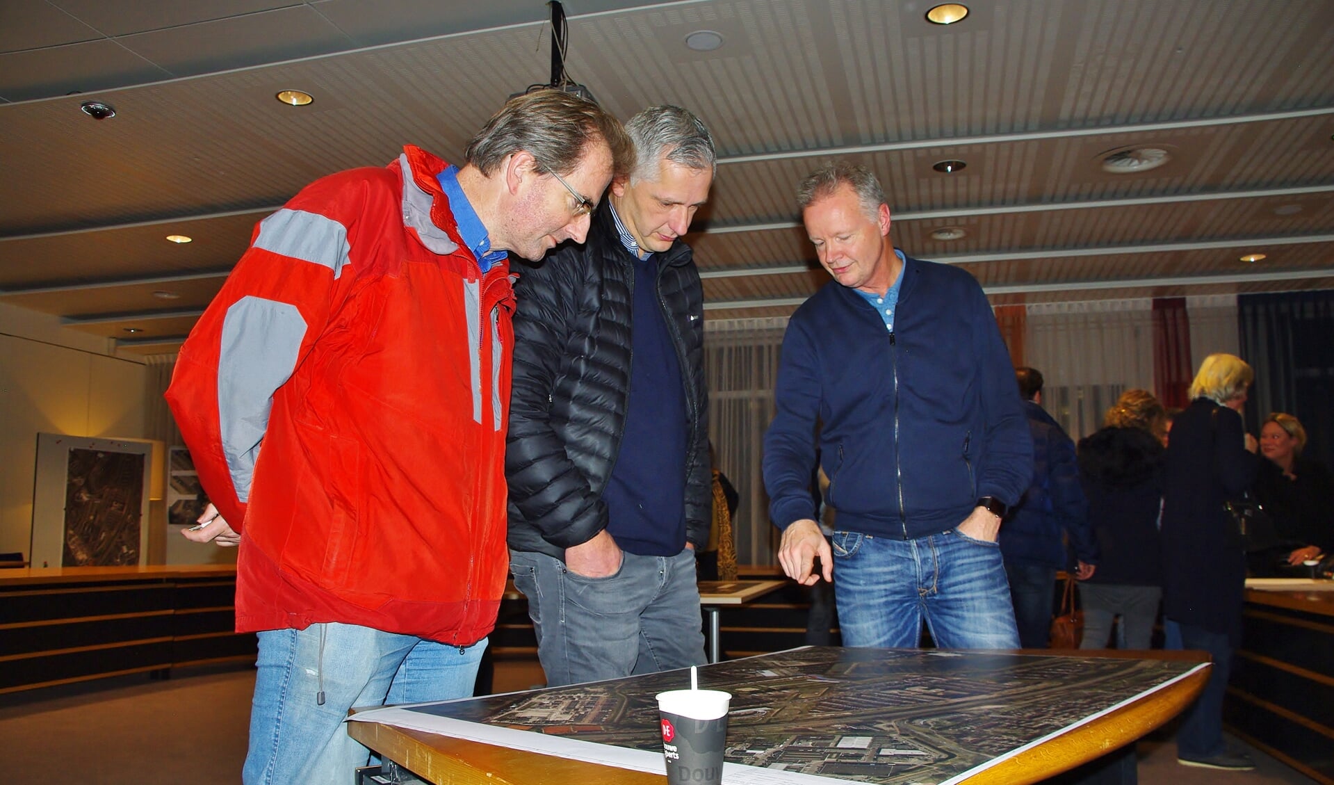 Bezoekers van de informatieavond bestuderen de kaart van Poelgeest met daarop de bouwweg. | Foto Willemien Timmers