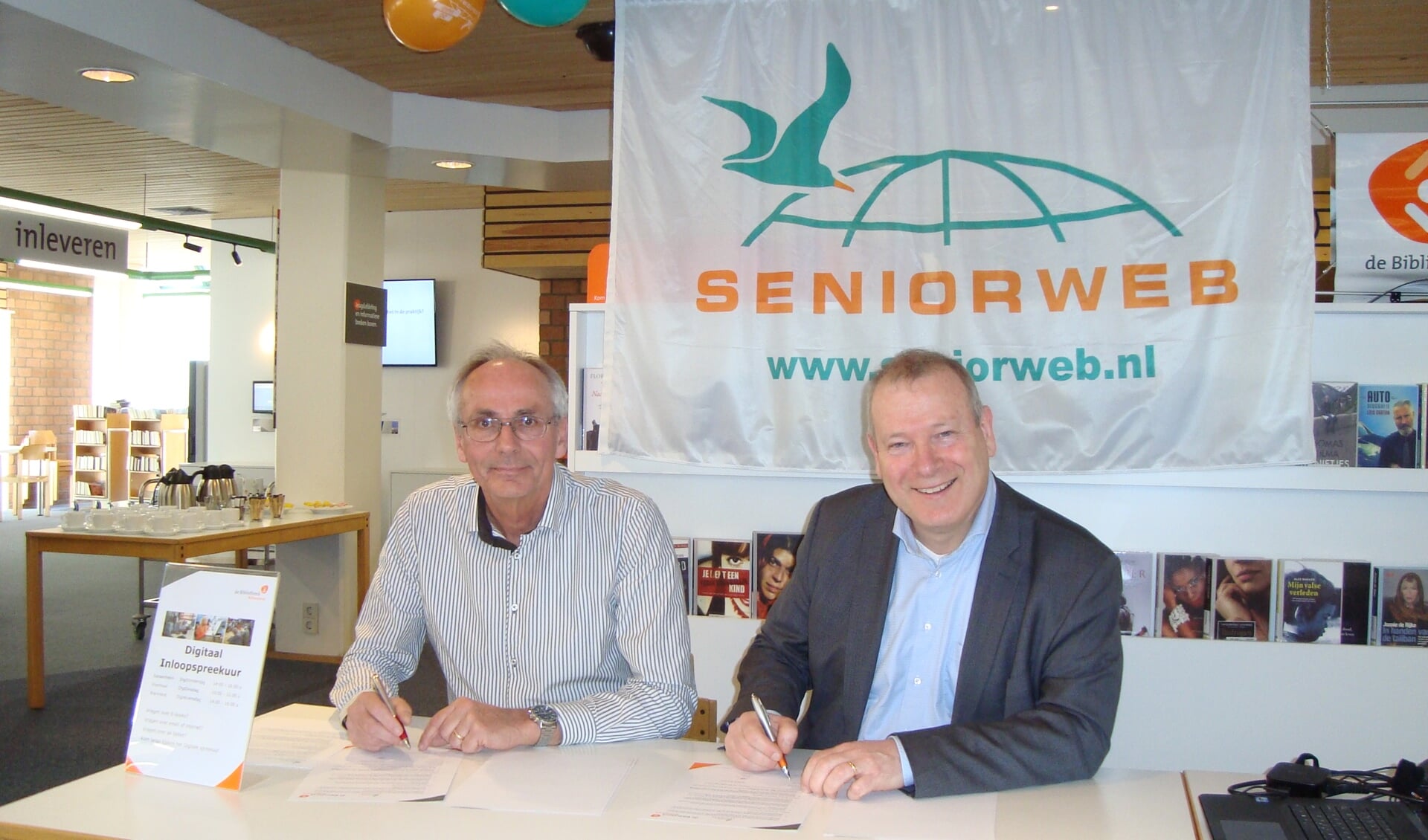 Leen van Goeverden (SeniorWeb) en Hans Portengen (Bibliotheek Bollenstreek) ondertekenen het eenjarig contract voor een SeniorWeb leercentrum in de bibliotheek van Sassenheim. | Foto: Marieke Voorn