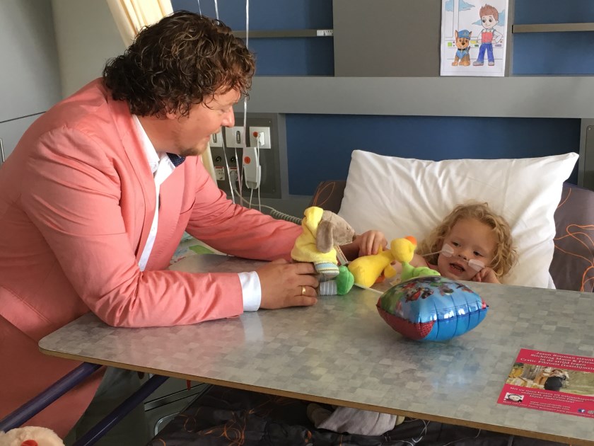 Jason Bouman geeft jonge patiënte een knuffel.