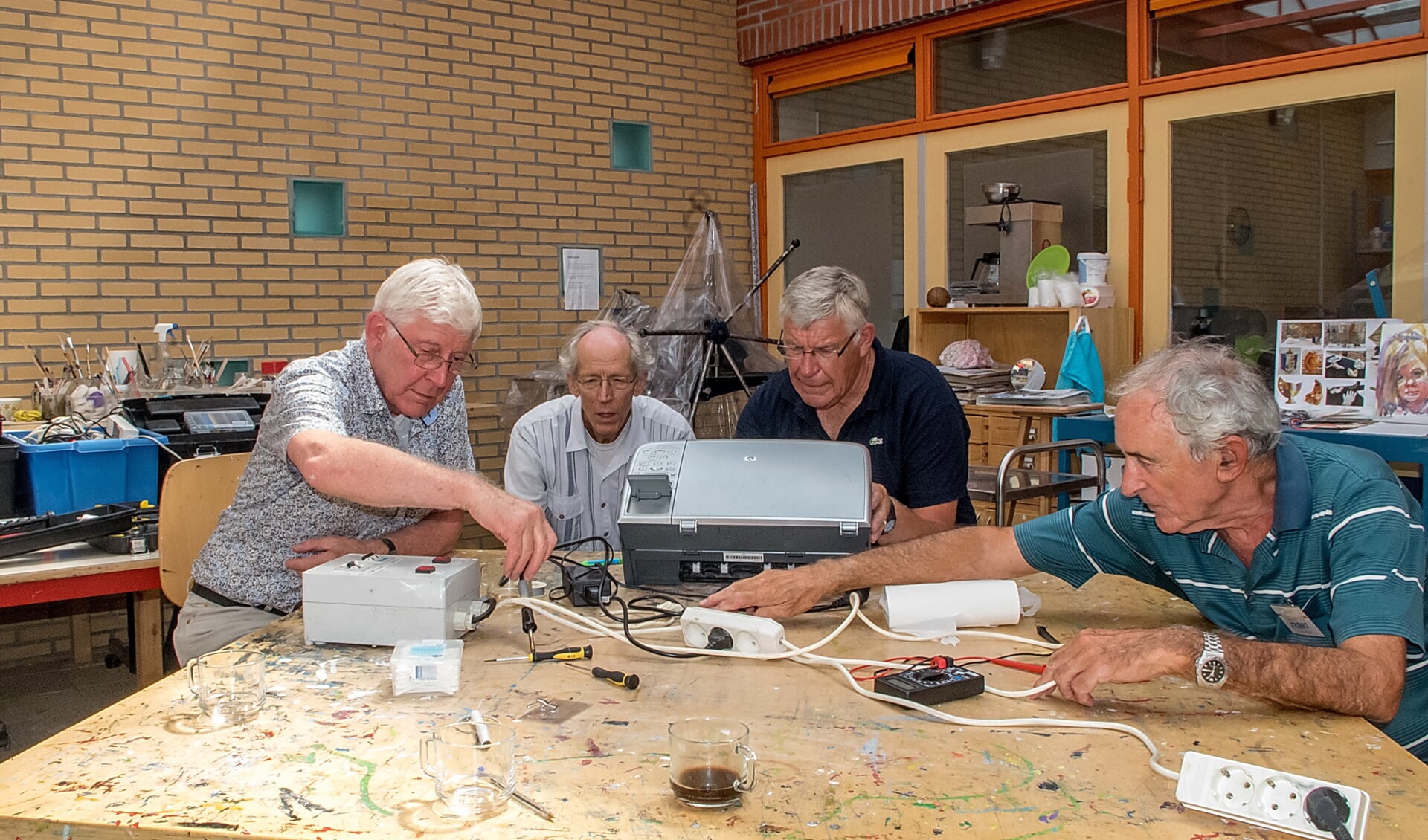 Vrijwilligers van het Repair Café buigen zich over een haperende printer.