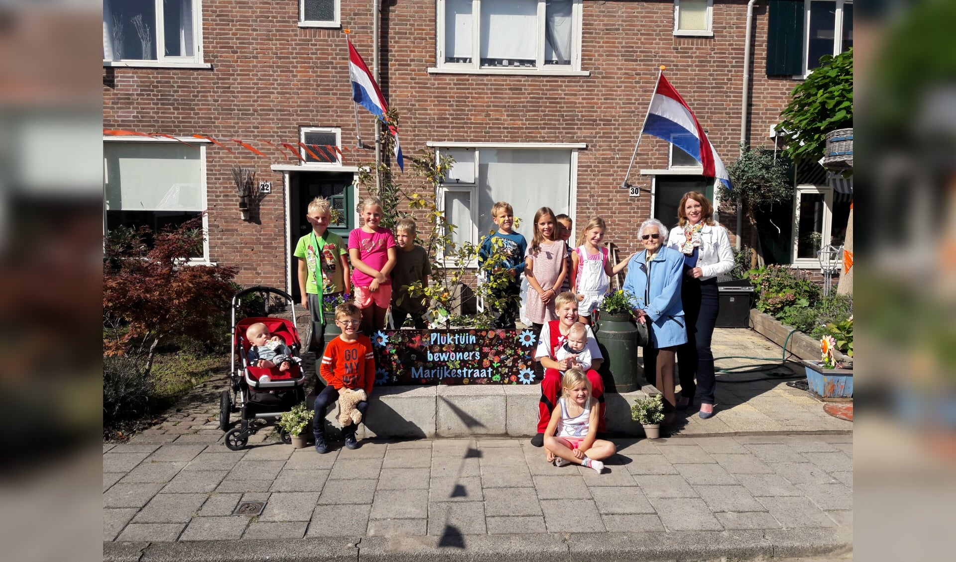 De kinderen uit de Marijkestraat onthullen de pluktuin, samen met burgemeester Breuer en mevrouw Smit (92). | Foto: MV