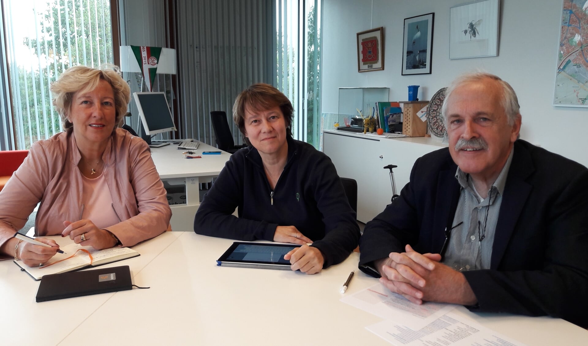 Opsteller Tanneke Schoonheim (midden) en voorzitter Emil Broesterhuizen van de Volksuniversiteit Leiderdorp nemen het dictee door met burgemeester Laila Driessen.