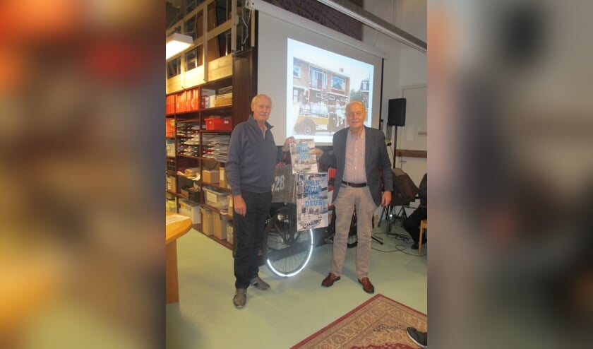 Peter vd Burg (l) overhandigt het eerst exemplaar aan Piet Warmerdam 'de melkboer uit de Kerkstraat'. | Foto: pr