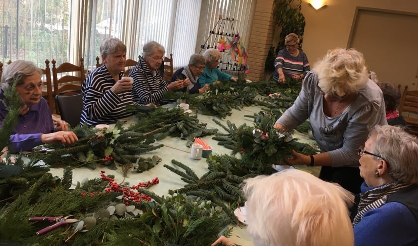 Deelnemers aan de slag met het groen voor in de kerststukjes. | Foto: pr.