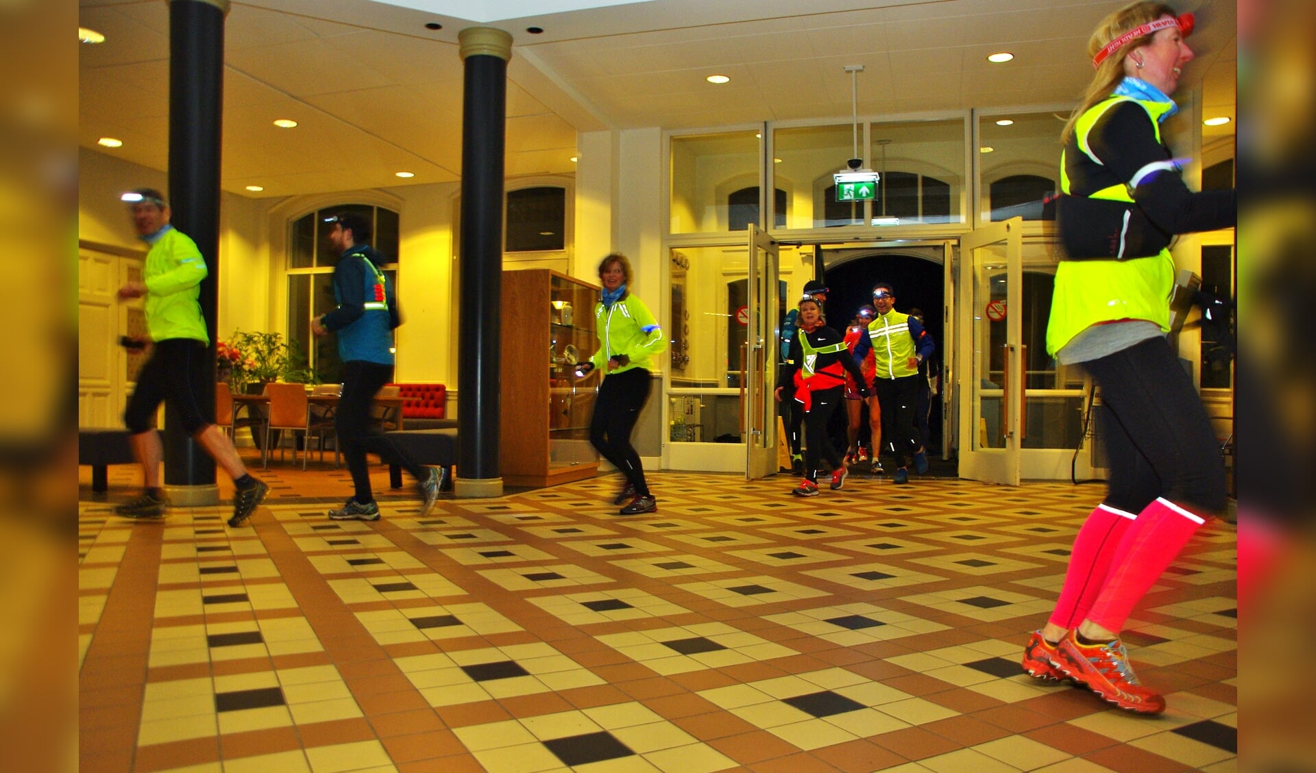 Deelnemers aan de eerste Oegstgeester nighttrail rennen door het gemeentehuis. | Foto Willemien Timmers