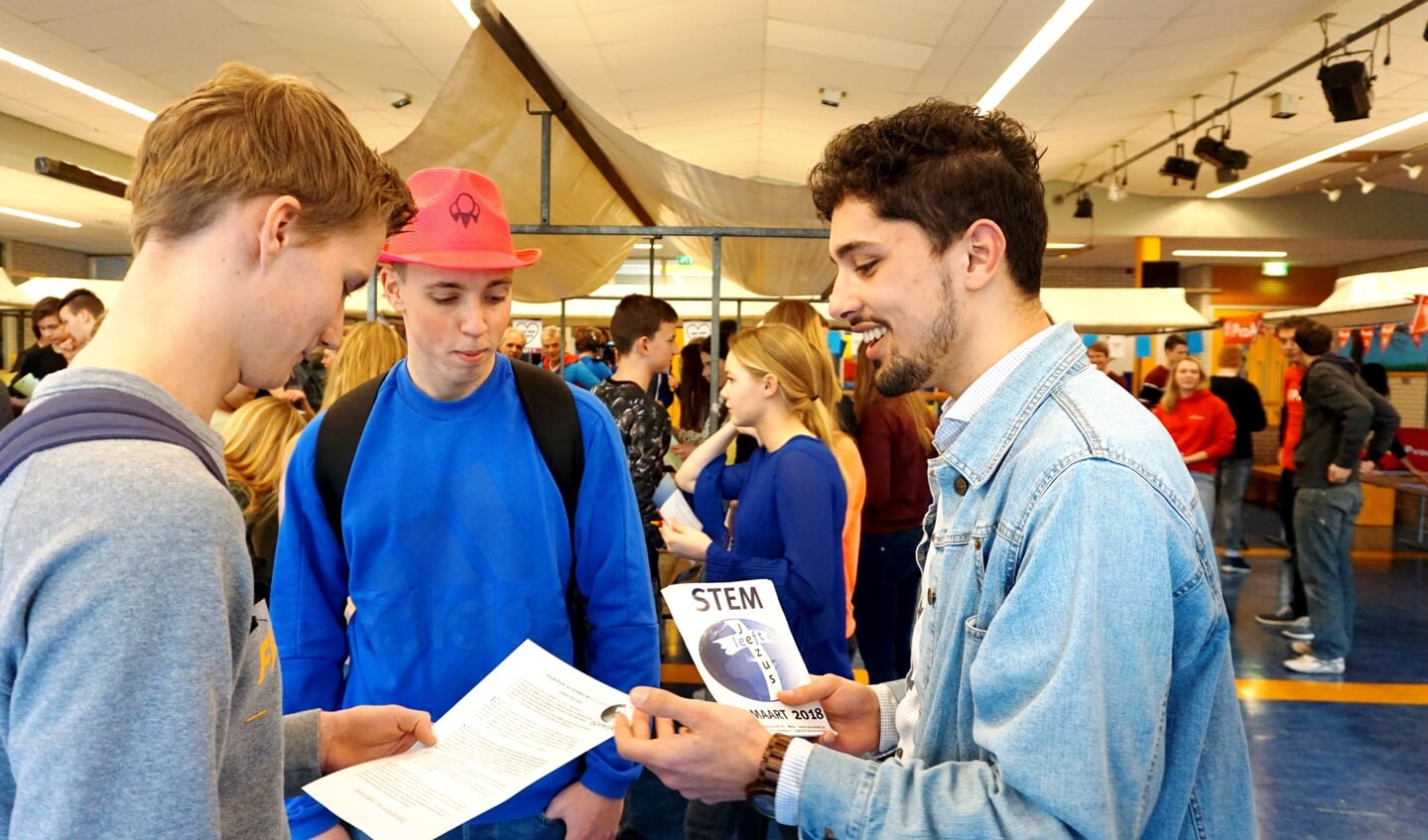Dylan Krayenoord (rechts) van Jezus Leeft vertelt twee leerlingen over de standpunten van zijn partij. | Foto: EvdV