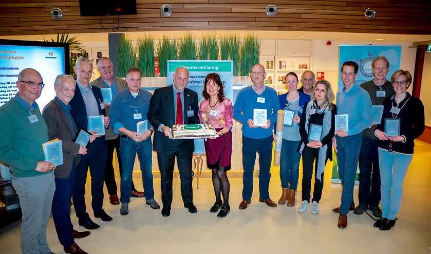 Dertien van de EA's met hun certificaten. Wethouder McDaniel staat al klaar met de taart. Tweede en derde van links staan Patrick Ploeg en Richard Hilhorst, EA's van 't Heerlijk Recht. | Foto: Johan Kranenburg