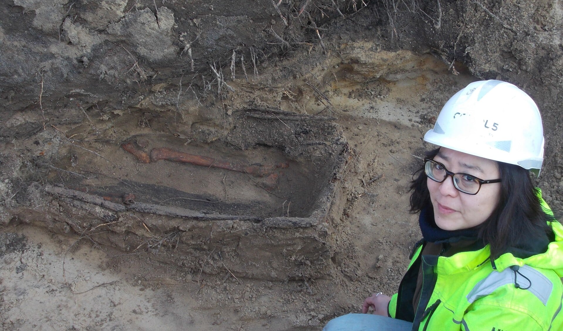 Archeologe Minja Hemminga bij de enige grafkist die de eeuwen in de 'verwoestende' zandgrond heeft getrotseerd. | Foto: Piet de Boer