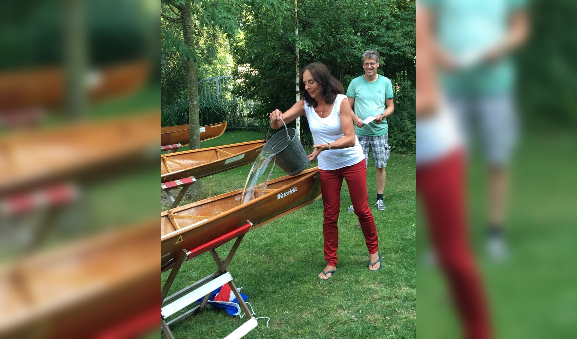 Coach Marike Kop doopt een van de boten met Grevelingwater. Op de achtergrond kijkt materiaalcommissaris Ton Schlief toe.