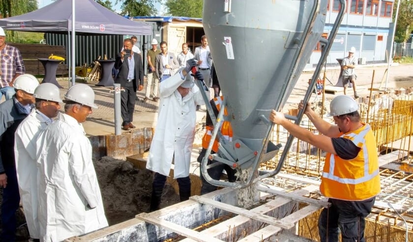 De Leiderdorpse wethouder Willem Joosten opent de kubel waardoor het beton in de bekisting voor de fundering kan stromen.