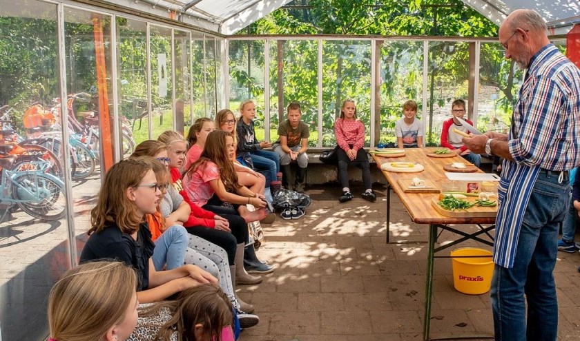 Vrijwilliger Bram Wijnmalen doet voor hoe je soepgroenten snijdt.