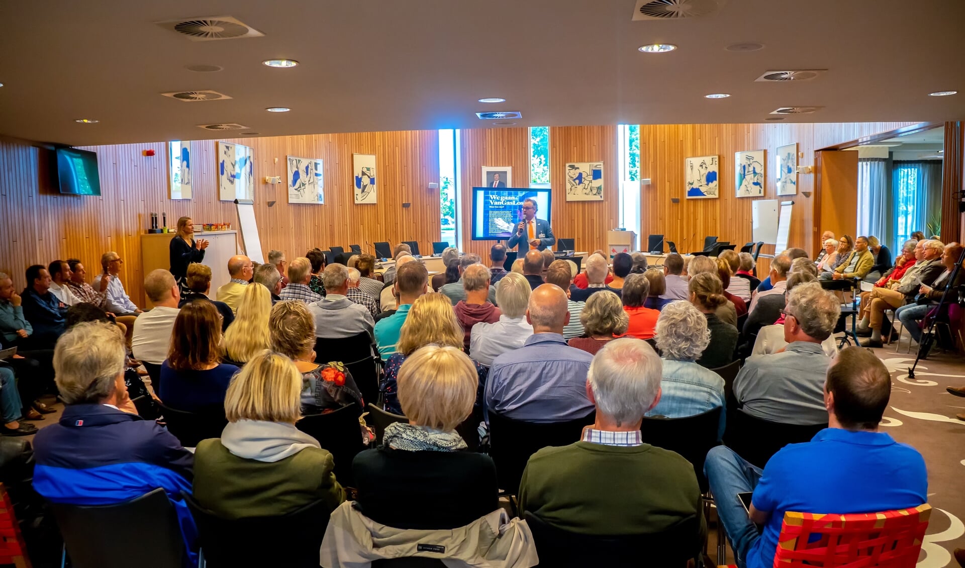 Wethouder Willem Joosten spreekt de eerste groep van ruim 150 bewoners toe. Links staat Maya van der Steenhoven van het programmabureau Warmte Koude Zuid-Holland.  