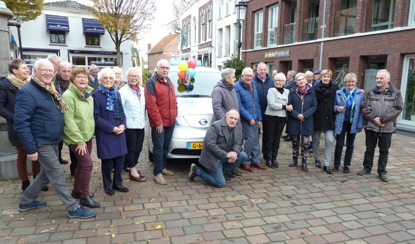 De seniorenbus wordt bijna aan het zicht onttrokken door de groep vrijwilligers.