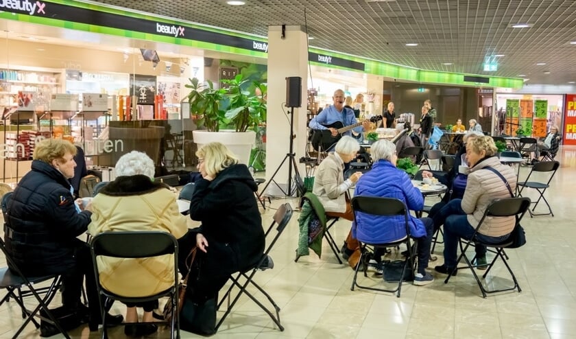 Tussen het winkelen door kon worden genoten van koffie met een petit-fours. Op de achtergrond gitarist Kees Kulk die bekende liedjes uit vroegere tijden zong.