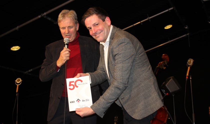 Gerard Alders overhandigt het jubileumboek aan wethouder Dennis Salman. | Foto: Annemiek Cornelissen
