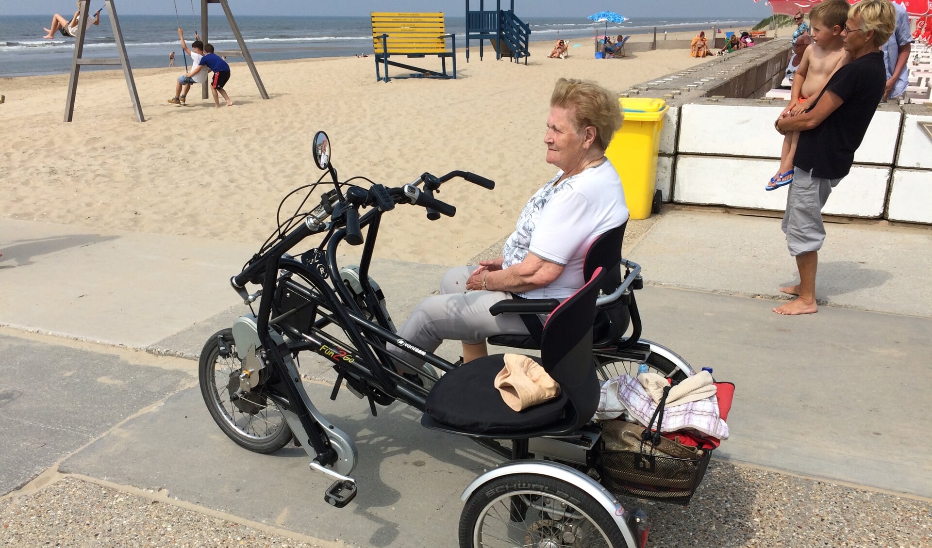 Een gast geniet van het mooie weer op het strand waar ze samen met een vrijwilliger van Fietsmaatjes Hillegom Lisse heen is gefietst.