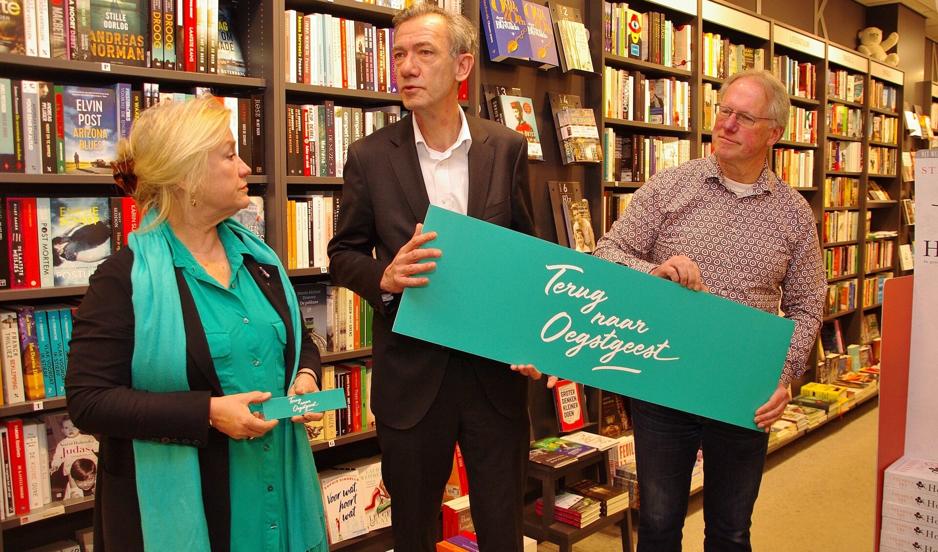 Wethouder Huizing neemt een grote boekenlegger in ontvangst van René Koek. Marjolijn van der Jagt kijkt toe. | Foto's Willemien Timmers