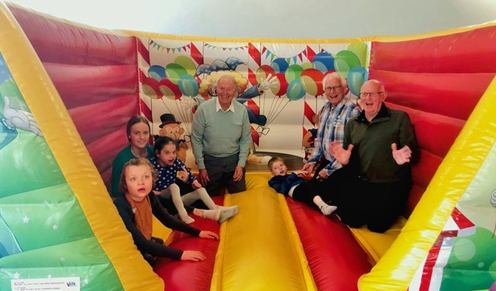 Opa Club bestuursleden Simon Brandt en Helmut Fellner en lid Joop Mensch hebben dit fantastische cadeau in het KDC in gebruik gesteld. Samen met de kinderen hadden zij veel plezier op het veelkleurige springkussen.