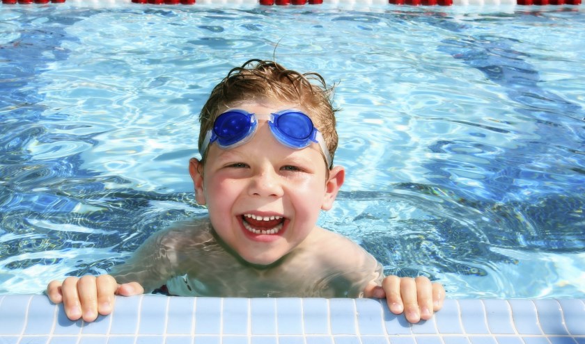 Smiling six year old boy in a sunny swimming pool