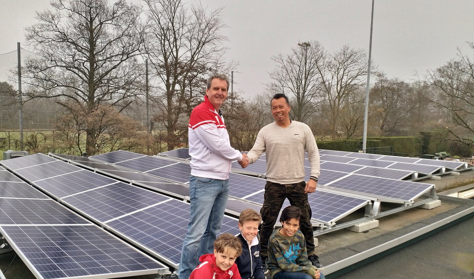 Erwin Gosenson van Solar Group draagt de zonnepaneleninstallatie over aan de voorzitter van OLTC Dick de Groot in het bijzijn van drie jeugdleden.